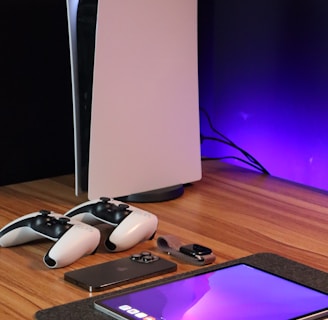 A sleek, modern setup featuring a gaming console with two controllers on a wooden surface. Nearby are a smartphone, smartwatch, tablet with a vivid screen, wireless earbuds, and a stylus. The background is illuminated with a soft purple glow.