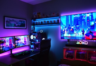 A vibrant gaming setup featuring multiple monitors displaying a cyberpunk cityscape. The room is illuminated with neon purple and blue LED lights, adding a futuristic ambiance. A custom-built PC with glowing components sits to the side, and shelves with collectible figurines are visible. A large digital screen on the wall shows an animated city scene, enhancing the immersive atmosphere.